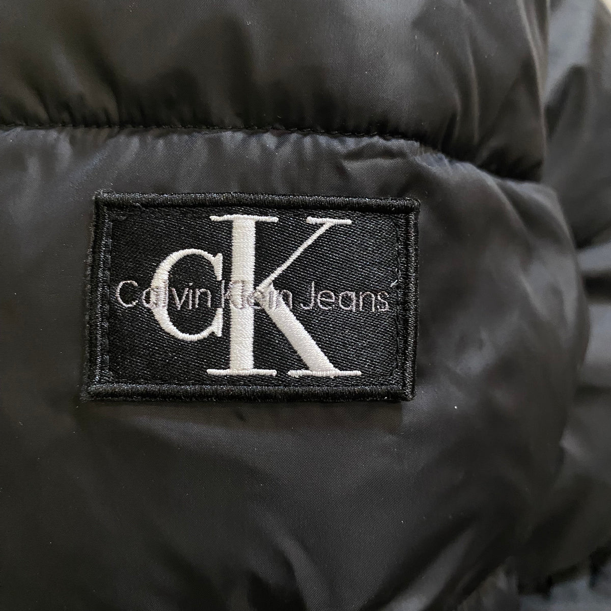 Calvin Klein Giubbotto Trapuntato con Cappuccio Junior IB0IB01276BEH Nero - logo manica